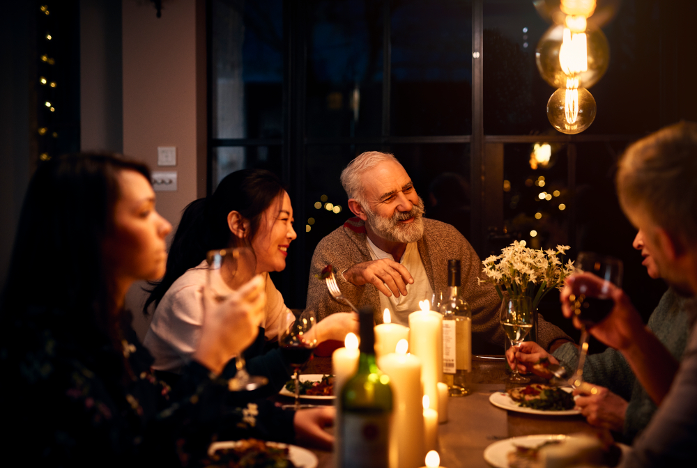 Cheerful Guests At Dinner Table Listening To Friend And Drinking Wine
