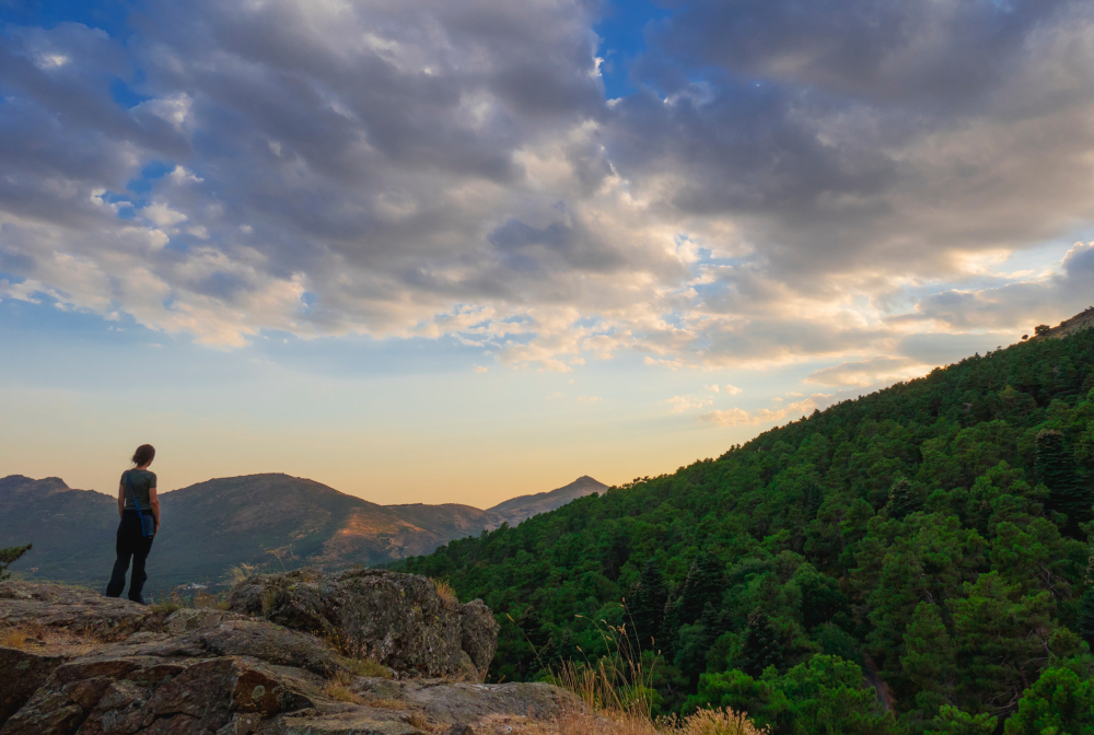 Rear View Of A Woman On A Rocks Watching Sierra De Guadarrama. Madrid, Spain. Mountains At Sunset With Clouds