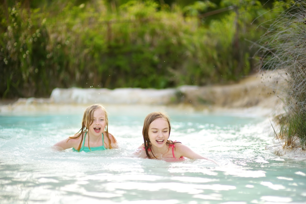 Two,young,sisters,bathing,in,natural,swimming,pool,in,bagno